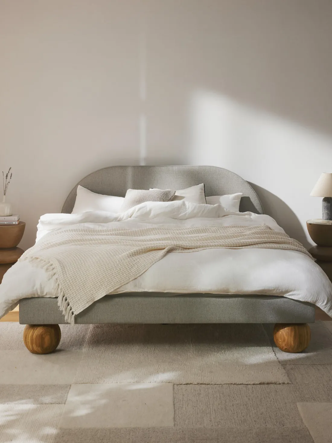 Cama tapizada con patas esfericas de madera Rena